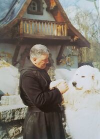 Le Père Albert Revet et son chien Urdox devant la « maison Blanche-Neige » à Riaumont